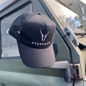 Black Stagshaw Land Rover trucker cap hanging on vehicle door mirror.