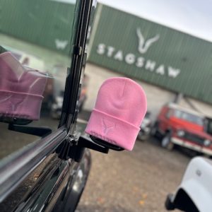 Pink Land Rover beanie hat displayed at Stagshaw Land Rover dealership, showcasing vehicle accessories and merchandise.